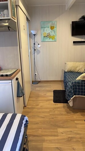 A bedroom with a bed, a desk, a chair, a floor lamp, a TV, and a painting on the wall. - La Tiny de Creissan - CREISSAN (CREISSAN)