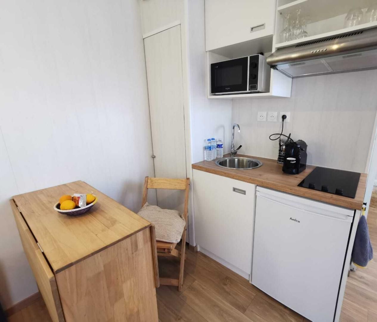 Une petite cuisine équipée comprenant un four à micro-ondes, un évier et un coin repas avec une chaise et une table.