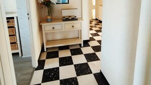 A hallway with a checkered floor, a white console table with a vase of flowers, and a framed picture on the wall. - Louisiana - SAUVIAN - B&B (SAUVIAN)