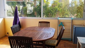 A round wooden table with four chairs, a small white table, and a drying rack. - Louisiana - SAUVIAN - B&B (SAUVIAN)