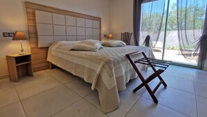 Un dormitorio con una cama grande, dos lámparas de noche, un cabecero de madera y vistas al exterior a través de un ventanal.