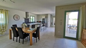 Una cocina moderna con comedor, un reloj grande y vistas a un patio exterior.