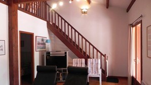 A living room with a wooden staircase, two black chairs, a television, and a framed picture on the wall. - Le Cabestan - VENDRES (VENDRES)
