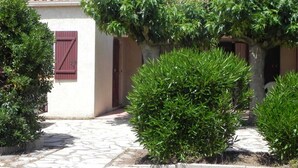 A building with a tiled roof, a red door, and a stone pathway leading to the entrance. - Le Cabestan - VENDRES (VENDRES)