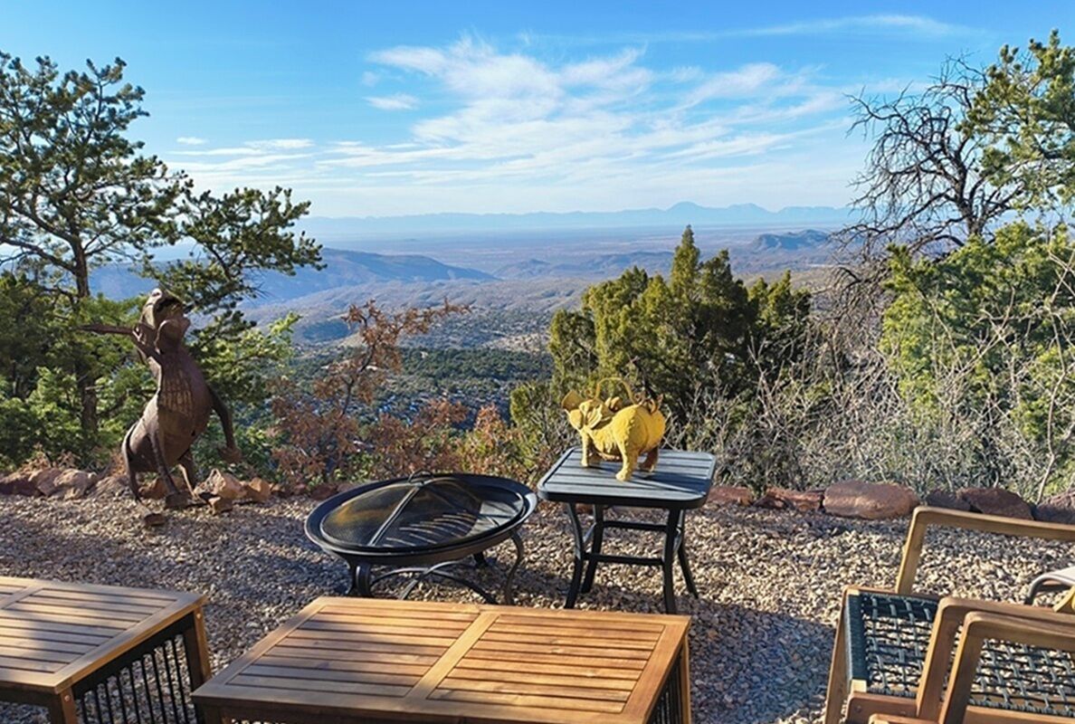 An outdoor seating area with a view of a valley, a fire pit, and a statue.