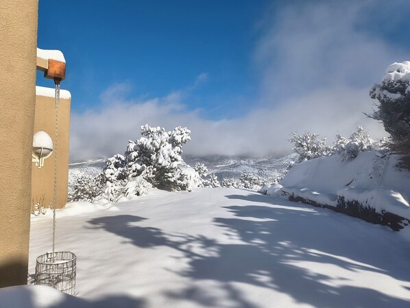 Paisaje nevado bajo un cielo despejado, un edificio con techo cubierto de nieve y una valla metálica.