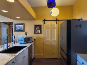 Una cocina compacta con lavamanos, microondas y refrigerador.