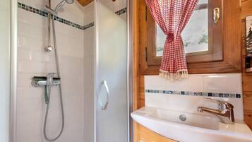 Un bagno con doccia, lavandino e una finestra con tende.