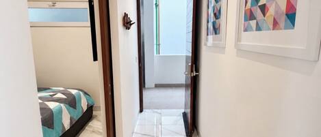 Un pasillo con una cama, una puerta y cuadros en la pared.