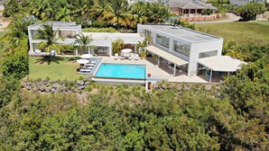 A modern two-story house with a swimming pool, surrounded by lush greenery and palm trees. - Atelier House  (Weston)
