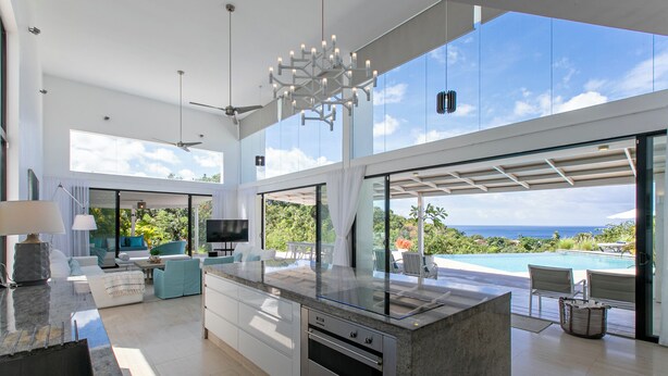 A modern kitchen with a large island, built-in oven, and a view of the ocean. - Atelier House  (Weston)