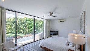 A modern bedroom with a large bed, a chair, a TV, and a ceiling fan. - Atelier House  (Weston)