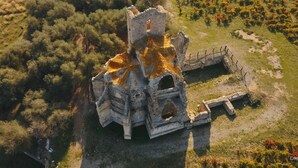An aerial view of a historic stone structure with a central tower, surrounded by dense vegetation and a fenced area. - La Celestine - PORTEL DES CORBIERES (PORTEL DES CORBIERES)