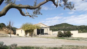 A single-story building with a flat roof, a small porch, and a gravel driveway. - La Celestine - PORTEL DES CORBIERES (PORTEL DES CORBIERES)
