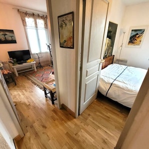 Una habitación de hotel con una cama, televisor, escritorio con silla y ventana con cortinas.