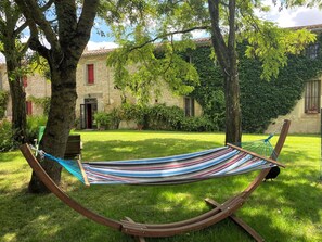 A hammock in a grassy area with a stone building in the background.