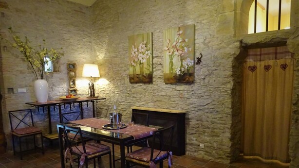 Comedor rústico con paredes de piedra, chimenea y una mesa dispuesta para dos.