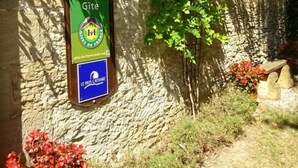 Una pared de piedra con un letrero que indica 'Gîte de France' y 'Le Pays Cathare'.