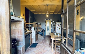 Una cocina estrecha con techo de madera, piso de baldosas y un comedor con mesa y sillas.
