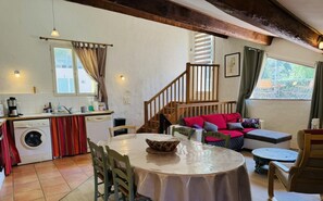 A cozy living area with a round dining table, a sofa, and a staircase leading to an upper level.