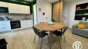 Una cocina moderna con armarios blancos, una mesa de comedor de madera y sillas negras.