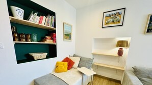 Un salón acogedor con un sofá, una mesita y estanterías llenas de libros y objetos decorativos.