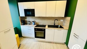 Una cocina compacta con armarios blancos, un microondas negro, un fregadero y una cafetera.