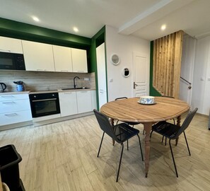 Una cocina moderna con armarios blancos, una mesa de comedor de madera y sillas negras.