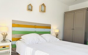 A neatly made bed with white bedding, a multicolored striped headboard, and two bedside lamps. - Lou Courredou - FERRALS LES CORBIERES (FERRALS LES CORBIERES)