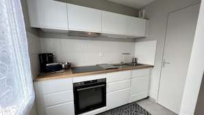 Una cocina moderna con armarios blancos, encimera de madera, horno integrado y campana extractora negra.