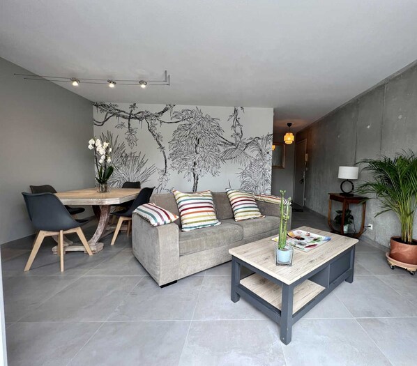 A modern living room with a sofa, coffee table, and dining area.