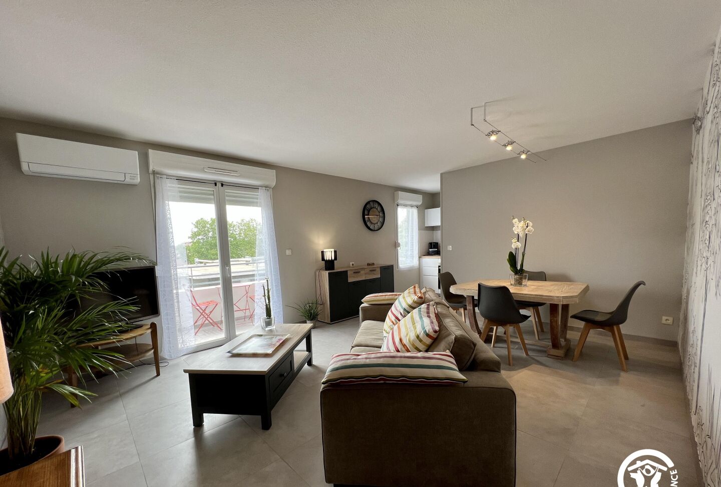 Uma sala de estar moderna com sofá, mesa de centro e área de jantar com cadeiras e uma mesa.