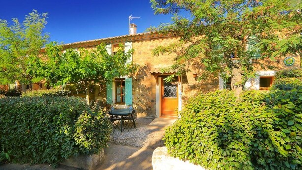 A rustic stone building with a garden patio, a wooden door, and a small table with chairs. - Domaine du Coude - SAINT ANDRE DE ROQUELONGUE (SAINT ANDRE DE ROQUELONGUE)