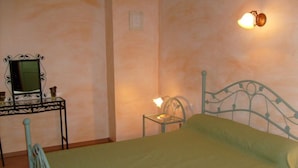 A bedroom with a metal bed frame, a bedside table with a lamp, and a wall-mounted light fixture. - Domaine du Coude - SAINT ANDRE DE ROQUELONGUE (SAINT ANDRE DE ROQUELONGUE)