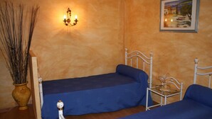 A room with two beds, a wall-mounted light fixture, a framed painting, and a vase with branches. - Domaine du Coude - SAINT ANDRE DE ROQUELONGUE (SAINT ANDRE DE ROQUELONGUE)