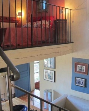 A room with a bed, a staircase, and a balcony.