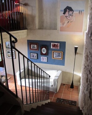 A staircase leading to a lower level with a white sofa and a framed picture collection on the wall.