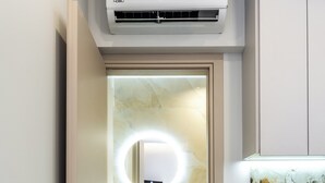 A modern bathroom with a built-in sink, a mirror with lights, a washing machine, and neatly folded towels. - Cozy Central Apartment by HOM54 (Heraklion)