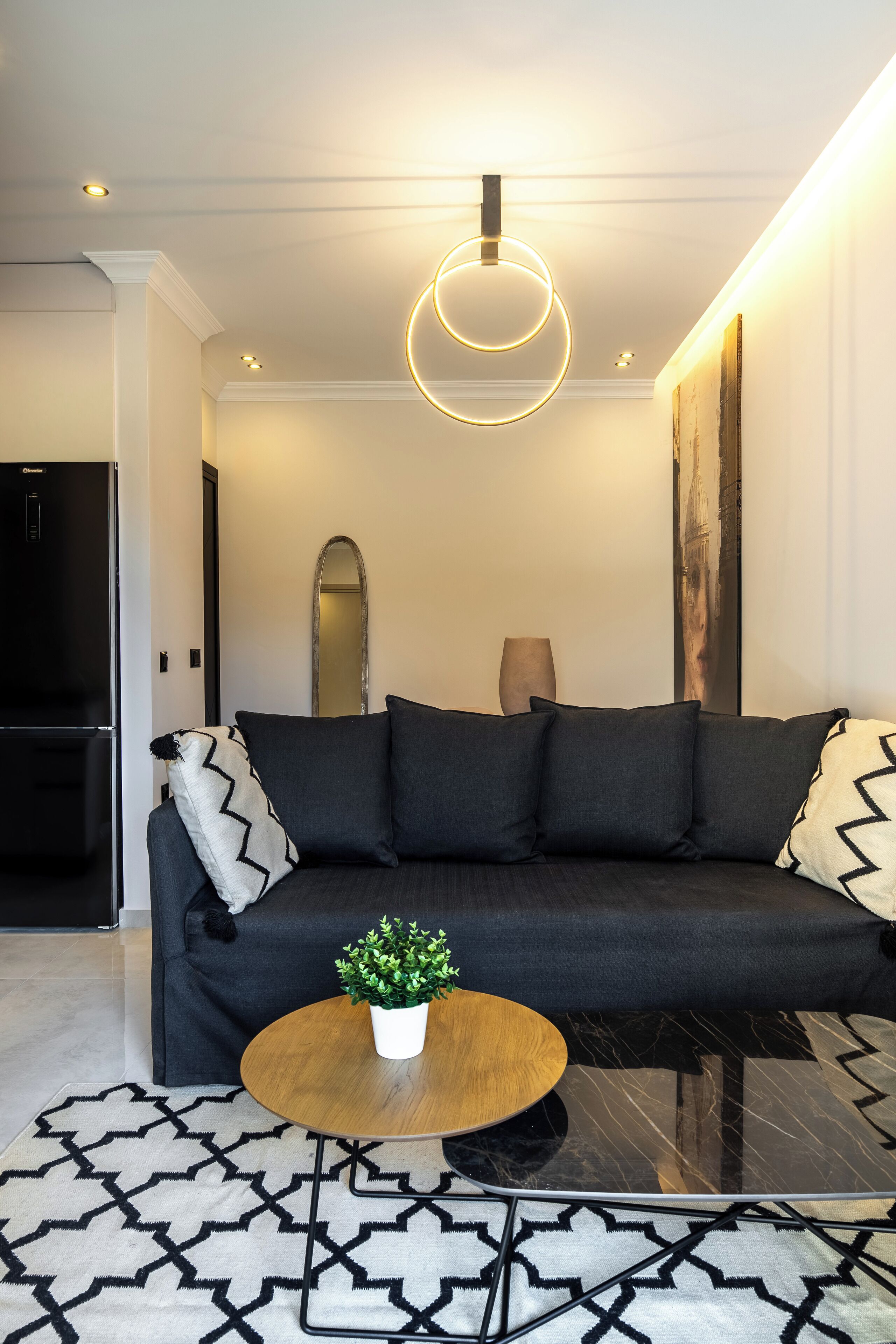 A modern living room with a black sofa, a round coffee table, and a patterned rug.