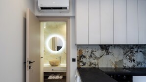 A modern bathroom with a built-in sink, a round mirror, and a towel rack. - Cozy Central Apartment by HOM54 (Heraklion)