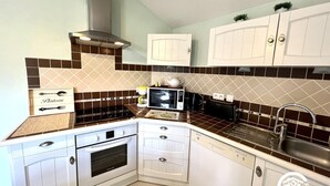 A kitchen with white cabinets, a stove, microwave, toaster, and a sink. - Les Jasmins - PENNAUTIER (PENNAUTIER)