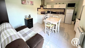 A compact living space with a kitchenette, a dining area, and a sofa. - Les Jasmins - PENNAUTIER (PENNAUTIER)