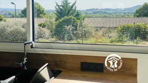 A modern kitchen with a large window overlooking a rural landscape.
