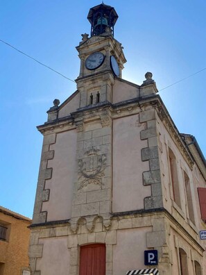 A historic building with a clock tower, a prominent crest, and a parking sign.