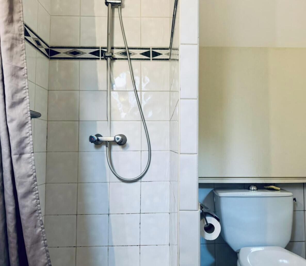 A bathroom with a shower, toilet, and tiled walls.