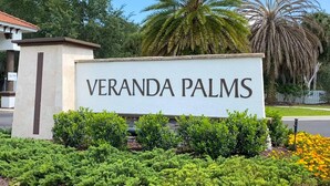 Een bordje voor Veranda Palms, met een helder uitzicht op de omliggende begroeiing en palmbomen.
