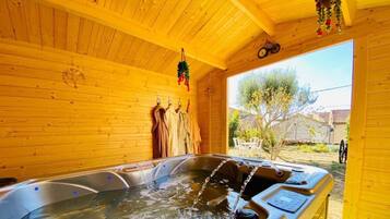 Una cabaña de madera con jacuzzi, paredes de madera y vistas al exterior.