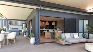 Een moderne buiten eethoek met een bank, stoelen en potplanten.