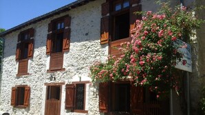 A stone building with wooden shutters and a sign indicating it is a restaurant.
