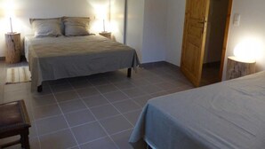 A bedroom with a bed, bedside tables, a wooden door, and a tiled floor. - Alquiere - PUILAURENS (PUILAURENS)